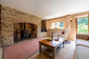 Butterfly Cottage في Wheddon Cross: غرفة معيشة مع موقد حجري وطاولة