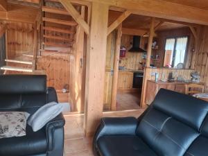 a living room with black leather furniture in a log cabin at Le Chalet in Laye