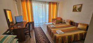 a hotel room with two beds and a desk at Hotel Venecia in Primorsko