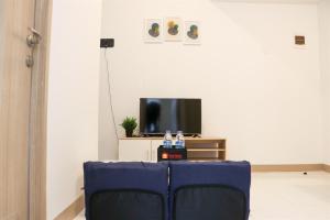 RawalembangComfort and Minimalist 2BR Apartment Tokyo Riverside PIK 2 By Travelio的客厅配有电视前配有蓝椅