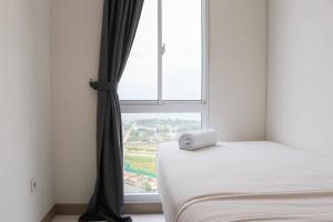 RawalembangComfort and Minimalist 2BR Apartment Tokyo Riverside PIK 2 By Travelio的带床和窗户的卧室