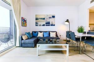ein Wohnzimmer mit einem blauen Sofa und einem Tisch in der Unterkunft Lovely Waterfront Private 2BR Apartment Yas Island in Abu Dhabi