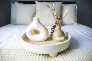 two white vases on a tray on a bed at 34 Evesham Road - Studio Apartment in Shottery