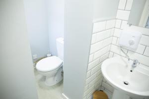 a white bathroom with a toilet and a sink at 34 Evesham Road - Studio Apartment in Shottery