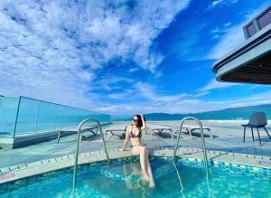 een vrouw in bikini zittend in een zwembad bij GRAND HYCHARMS Serviced 2BR APARTMENT View Cầu Nhơn Hội in Quy Nhon +16 foto's