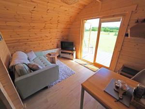 a living room with a couch and a television in a log cabin at Orchard Hideaway, Bielby, York in Everingham