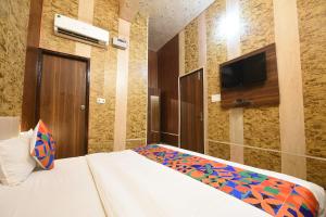 a bedroom with a bed and a flat screen tv at FabExpress The Grand Palace in Faridabad