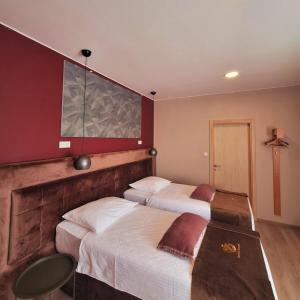two beds in a hotel room with red walls at Boutique Hotel St Georgije in Banja Luka