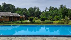 a villa with a swimming pool in front of a resort at Happy Man Village in Bentota