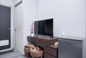a living room with a television and two stools at Nice and Simply 2BR at Green Bay Pluit Apartment By Travelio in Jakarta