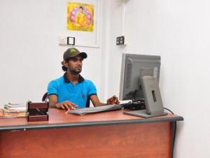 a man sitting at a desk with a computer at Sun Up Hotel in Katunayake