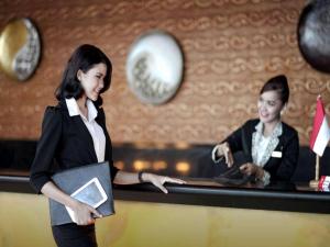 une femme debout devant un comptoir dans l'établissement Grand Basko Hotel, à Minangkabau International Airport 118 autres photos