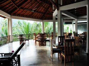 a restaurant with tables and chairs and a balcony at Brook Boutique in Sigiriya