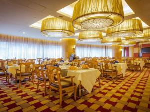 a dining room with tables and chairs and chandeliers at Wuhan Premier Mayflowers Hotel in Wuhan