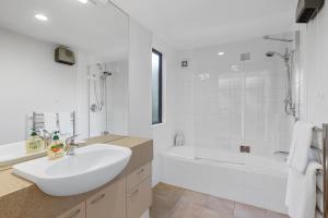 Un baño blanco con lavabo y bañera. en *** LAKE VILLA 458 ***, en Hanmer Springs