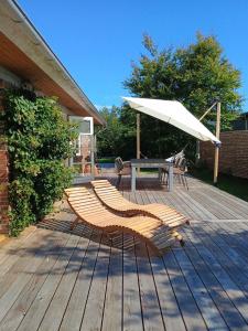 a wooden deck with a table and an umbrella at Family-Friendly Home Near Beach, Forest, Harbour in Ålbæk