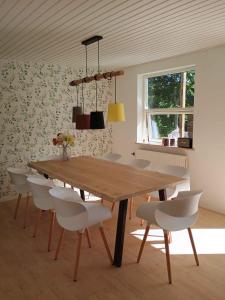 a dining room with a wooden table and white chairs at Family-Friendly Home Near Beach, Forest, Harbour in Ålbæk