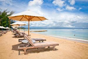 a beach with chairs and an umbrella and the ocean at Sanur Ayu Hotel in Sanur