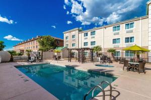 a pool in front of a building with tables and chairs at Comfort Inn Tucson Central in Tucson