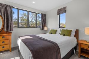 Un dormitorio con una cama grande y ventanas. en *** LAKE VILLA 460 ***, en Hanmer Springs