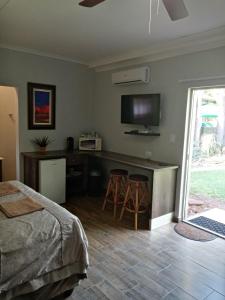 a bedroom with a bed and a desk with a tv at De la Rose Guesthouse in Lephalale