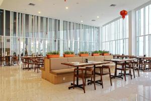 a restaurant with tables and chairs and large windows at BBC Hotel Lampung Bandar Jaya in Gunungsugih +39 photos