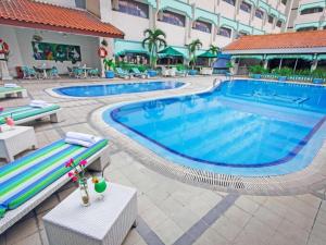 a swimming pool in a hotel with tables and chairs at Kartika Chandra Hotel in Jakarta