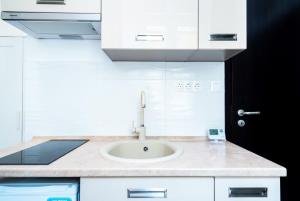 a white kitchen with a sink and a black door at Modern Intimate Studio in the center in Budapest +11 photos