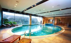 ein großes Schwimmbad in einem Gebäude mit Fenstern in der Unterkunft Cixi Hangzhou Bay Hotel in Hejiao