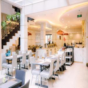 a restaurant with tables and chairs and a staircase at Grand Malioboro Yogyakarta in Yogyakarta
