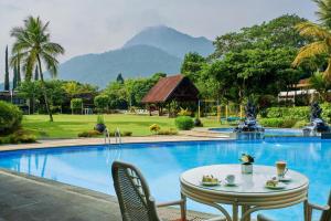 a table and chairs next to a swimming pool at eL Hotel Kartika Wijaya Batu in Malang