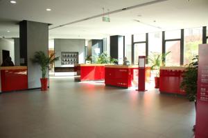 an empty lobby with red counters and potted plants at Intercity Hotel Qingdao in Huangdao
