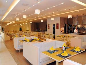 a restaurant with tables and chairs and a man in a kitchen at Oasis O.City Hotel in Shenzhen