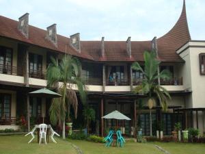ein Gebäude mit Stühlen und Sonnenschirmen davor in der Unterkunft Campago Resort Hotel in Bukittinggi