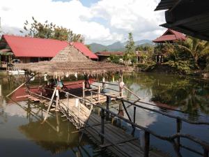 ein Gebäude mit Strohdach auf dem Wasser in der Unterkunft Phu Resort in Ban Choko