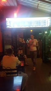 Un hombre parado en un bar hablando con un hombre. en Cheaper Room, en Surat Thani