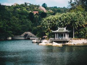 a temple in the middle of a river with a bridge at Rezen Hotel Huaxia Xiamen in Xiamen