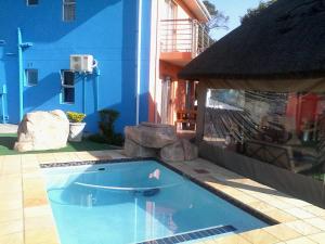 a swimming pool in front of a blue building at Lodge Bellagio in Mthatha