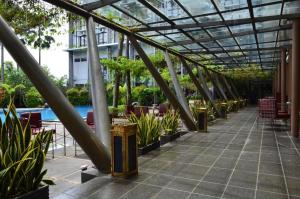 Un patio con techo de cristal con plantas y una piscina. en Ratu Hotel Serang, en Banjar