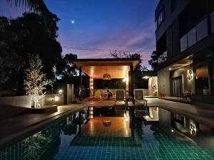 a house with a swimming pool at night at Villa Gris Pranburi in Pran Buri