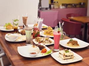 a wooden table with plates of food and drinks at Graha Cempaka Boutique Hotel in Surabaya