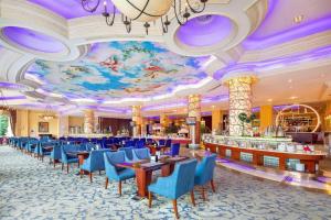 a restaurant with blue chairs and a ceiling with a mural at Country Garden Phoenix Hotel Chizhou Jiuhua Mountain in Chizhou