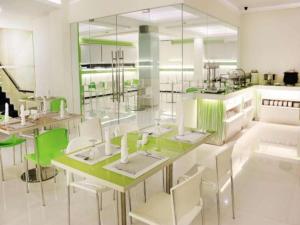 a dining room with white tables and green chairs at Everbright Ambon Hotel in Ambon