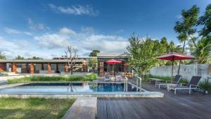 a pool with chairs and umbrellas next to a house at Lipda Resort in Ban Nong Hin