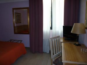 a bedroom with a bed and a desk with a lamp at Hotel Ascot in Binasco