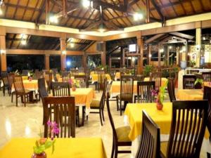 ein Restaurant mit Tischen und Stühlen mit gelben Tischen in der Unterkunft Kalibaru Cottages in Banyuwangi