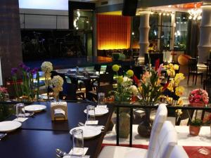 a dining room with tables and chairs and flowers at Florida Hotel in Hat Yai