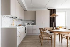 a kitchen with white cabinets and a table and chairs at Sataman timantti in Oulu