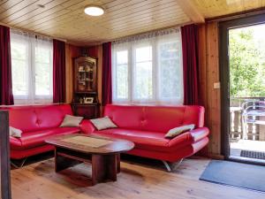 a living room with a red couch and a table at Chalet Zur Säge by Interhome in Albinen