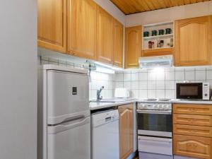 eine Küche mit Holzschränken und einem weißen Kühlschrank in der Unterkunft Holiday Home Vuokatinportti a 12 by Interhome in Lahdenperä